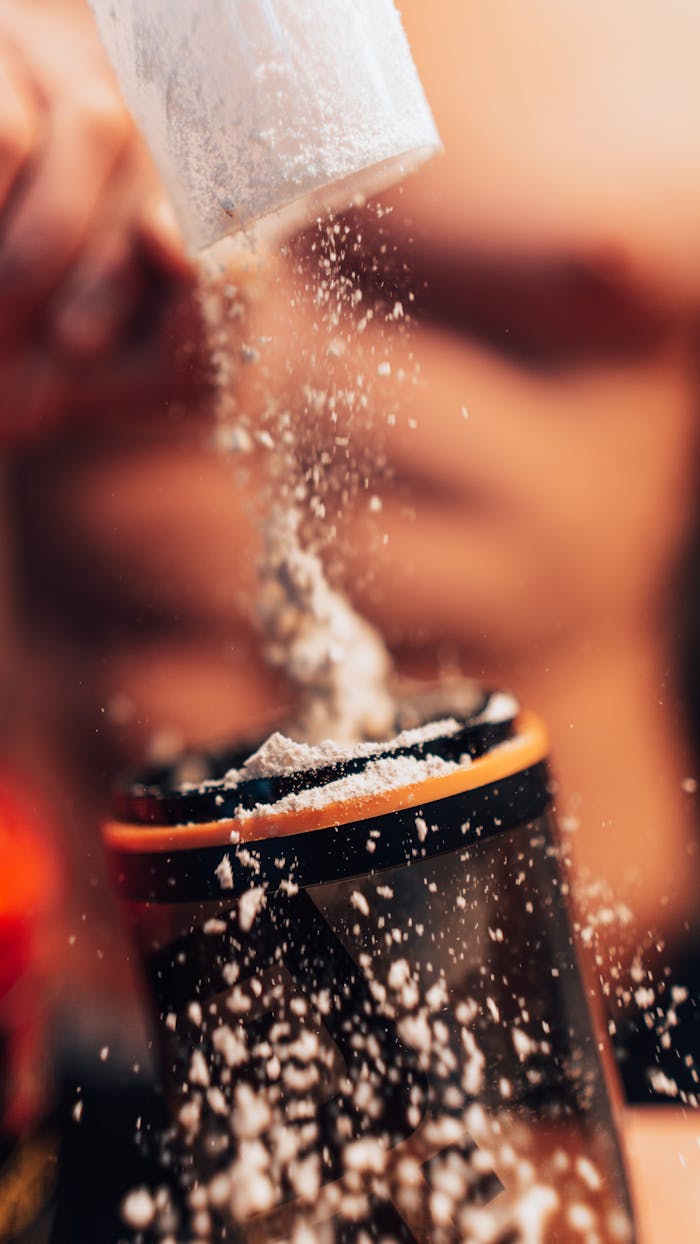 Dynamic shot of protein powder being added to a shaker, fitness concept.